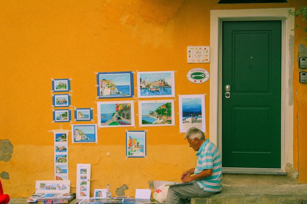 man paints in front of yellow wall